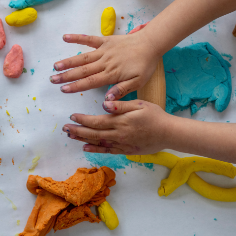 Child's hands rolling colorful playdough