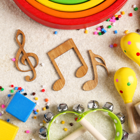 Wooden music notes, a rainbow, and maracas and tambourines with confetti around it