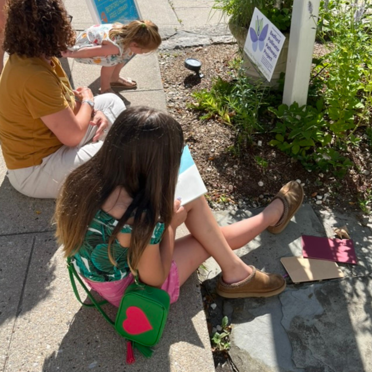 Three people sitting and sketching next to the Library's garden