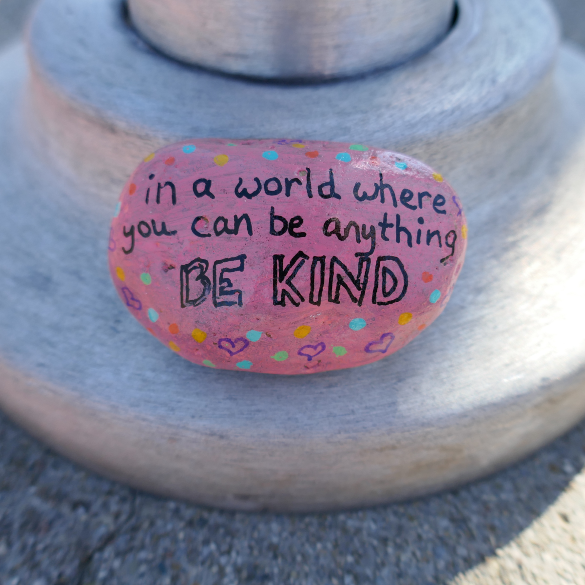 Image of a rock hand painted with the words "In a world where you can be anything, be kind"