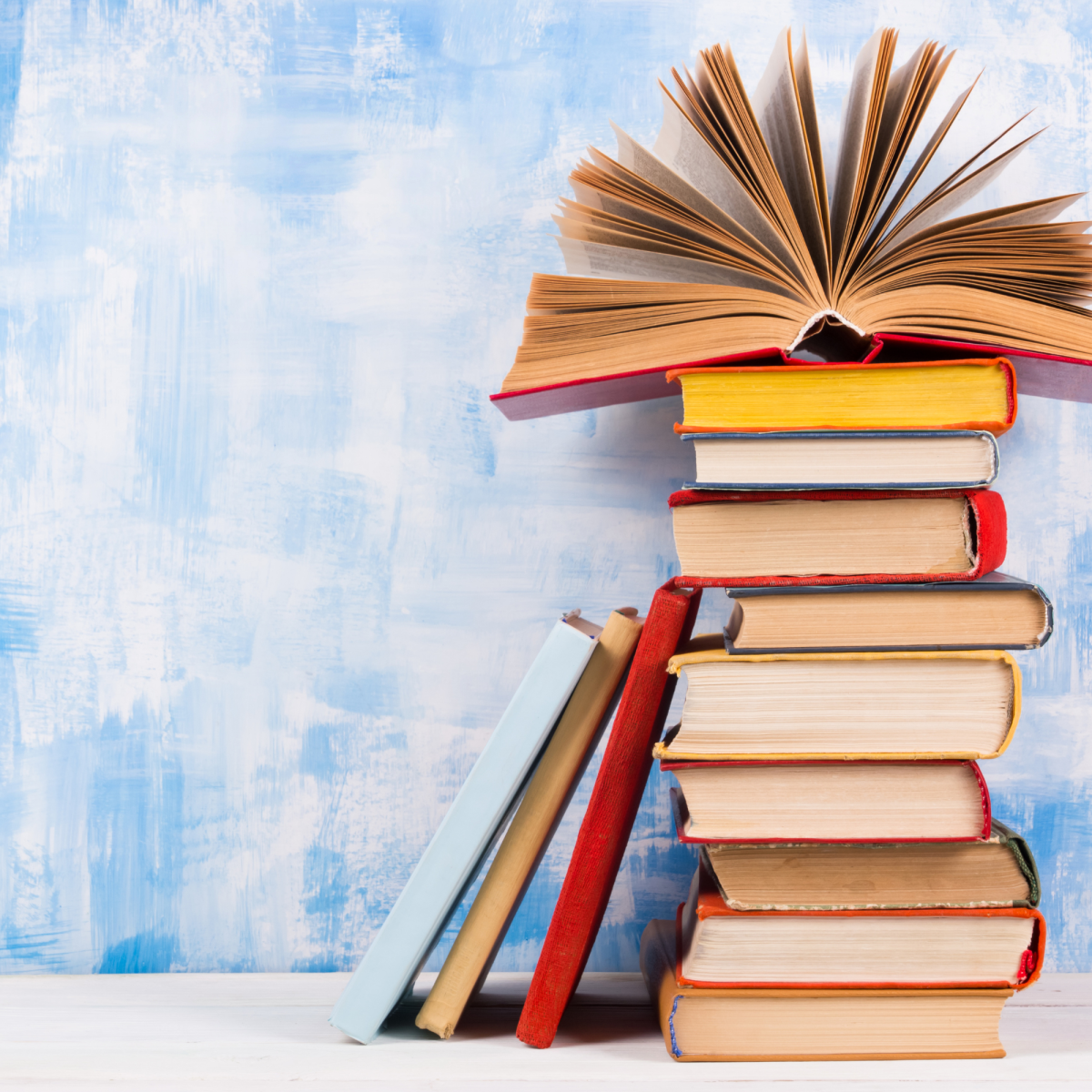 Stack of books in front of a blue and white painted background